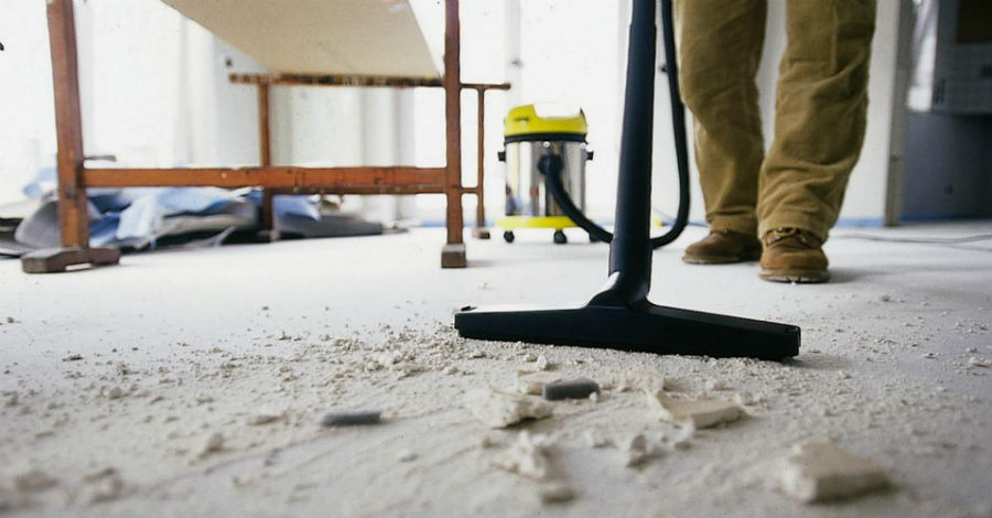 Technician using commercial vacuum to remove fine dust from flooring in a newly renovated Jeffersontown office space